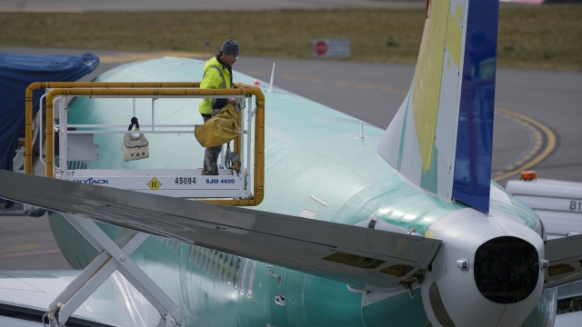 An employee checks a Boeing 737 MAX 9 airplane from a lift outside the government contractor's factory