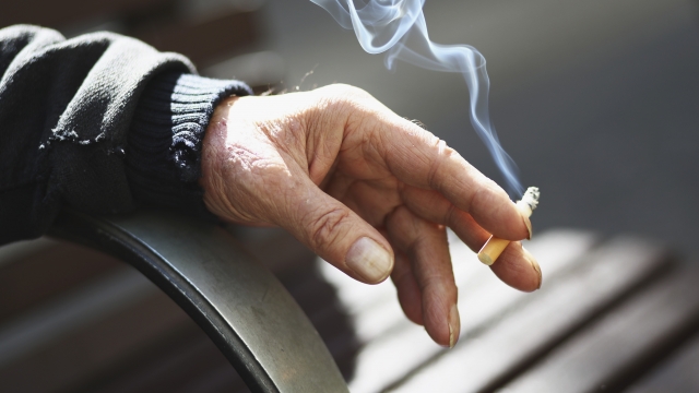 A man holds a lit cigarette