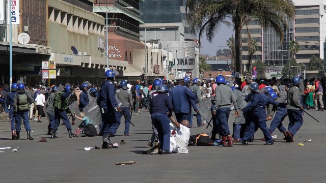 Opposition demonstrators lie in the street of Harare, Zimbabwe, as riot police drive back the protest