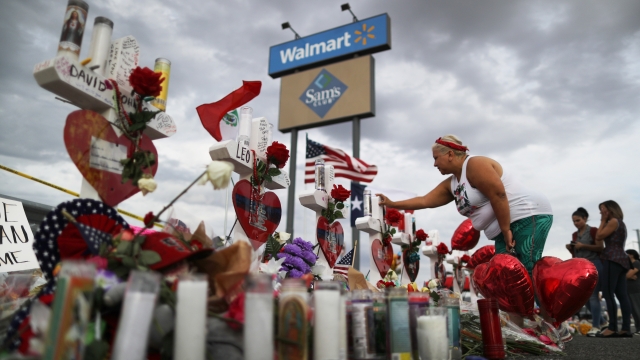 A woman touches a cross at a makeshift memorial for victims outside Walmart.