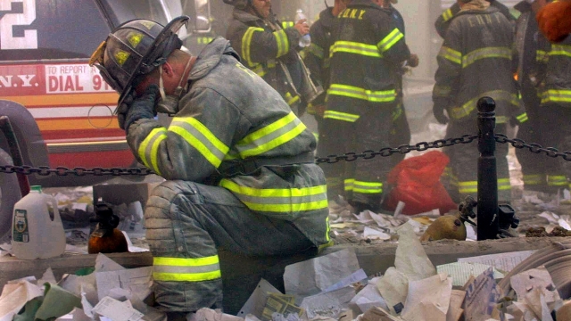 A firefighter kneels and covers his face at the rubble of the World Trade Center in 2001.
