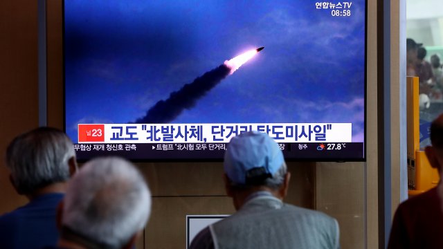 People watch a TV showing a file image of a North Korean missile in August 2019