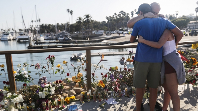 People embrace near a memorial for the victims of the California boat fire