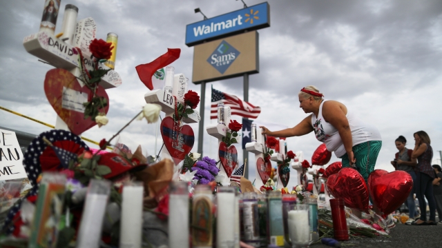 A woman touches a cross at a makeshift memorial for victims outside Walmart