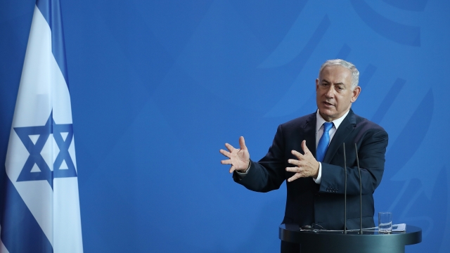 Prime Minister Benjamin Netanyahu stands next to Israel flag