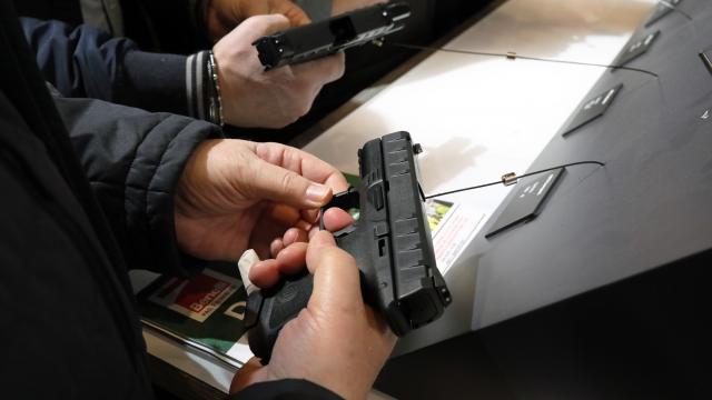 People hold handguns at a trade show