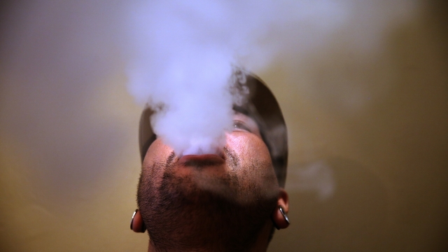A man blows vapor from an e-cigarette