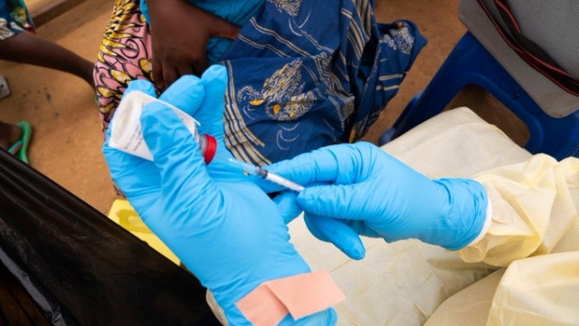 A person holds a vial and needle for an Ebola vaccine