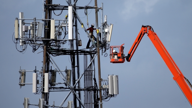 A worker climbs on a cellular communications tower