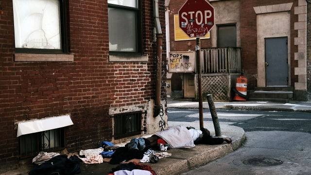 A homeless person sleeps on the sidewalk
