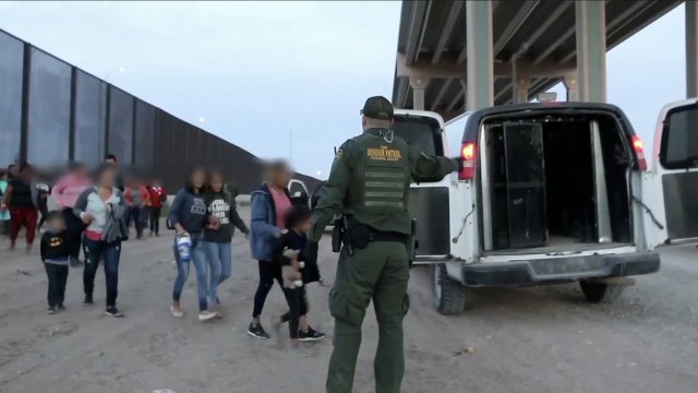 A Customs and Border Patrol agent directs undocumented immigrants into a CBP vehicle at the southern U.S. border