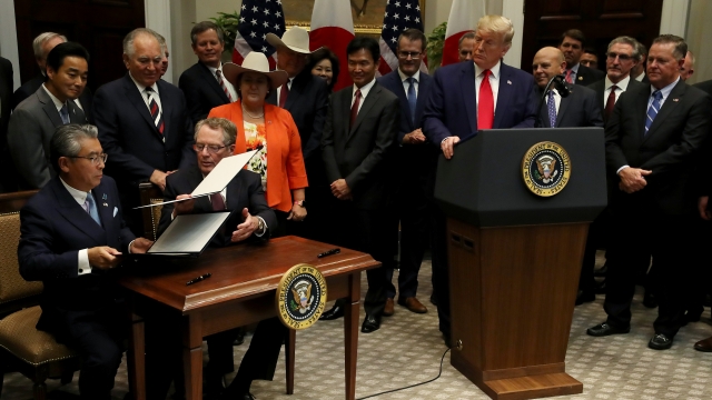President Donald Trump watches as U.S. and Japanese representatives sign trade agreements.