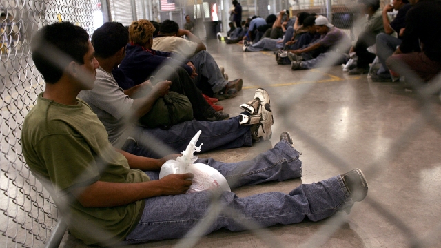 Migrants sit in custody
