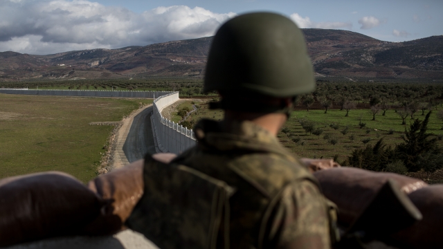 Turkish soldier looks over border wall into Syria