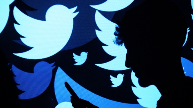The Twitter logo projected onto a man