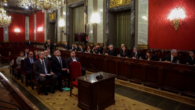 Former Catalan separatist leaders sit on the front bench at the beginning of their trial.