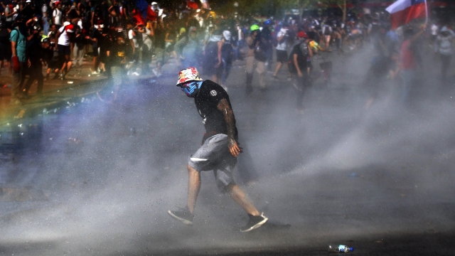 Chilean protestors cross street amid water fire blast on Thursday.