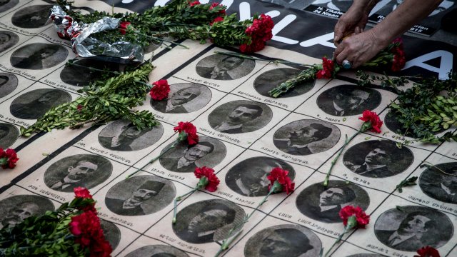 A woman lays roses over the portraits of victims.