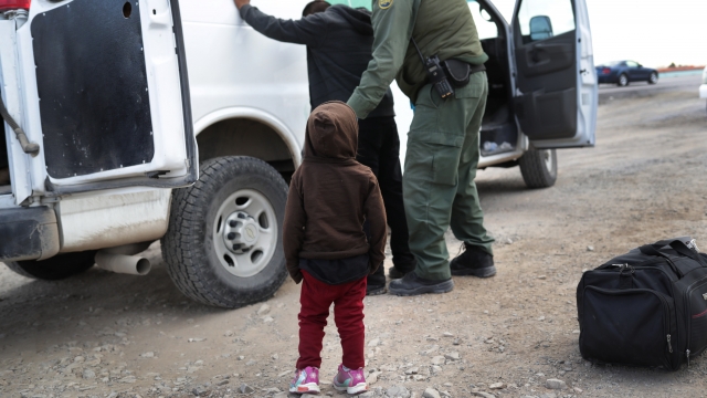 A child watches as a U.S. Border Patrol agent searches an immigrant.