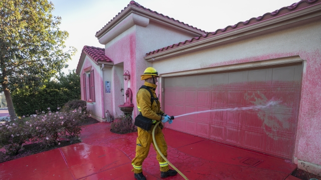 Firefighter washes fire retardant from house Wednesday near grasslands fire in Simi Valley, California.