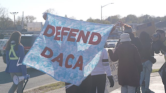 DACA supports hold a "Defend DACA" banner during a march