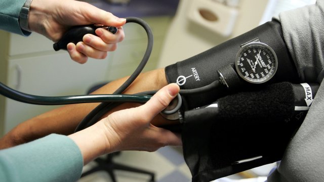 A nurse reads a blood pressure gauge.