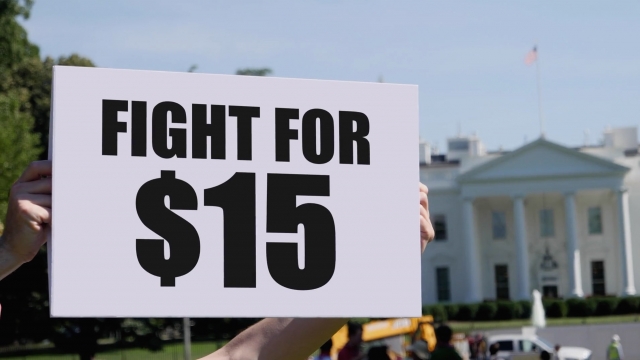 A person holds a sign that reads, "Fight For $15."