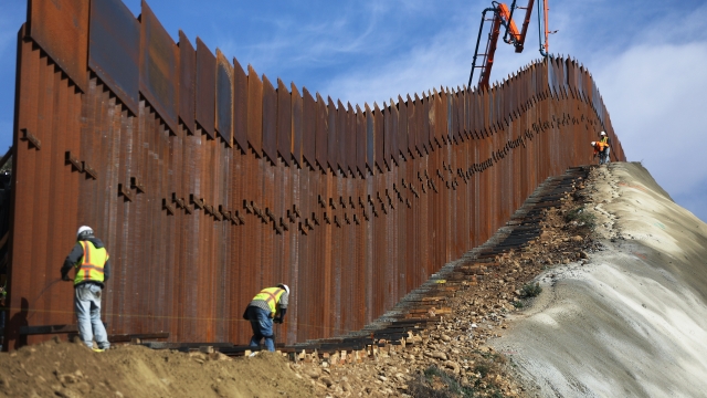 Construction crew members build a border barrier