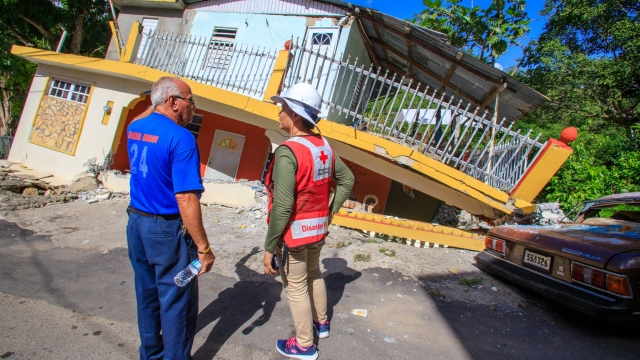 A man shows a Red Cross volunteer how his sister’s home was damaged in the recent series of earthquakes that hit the island.