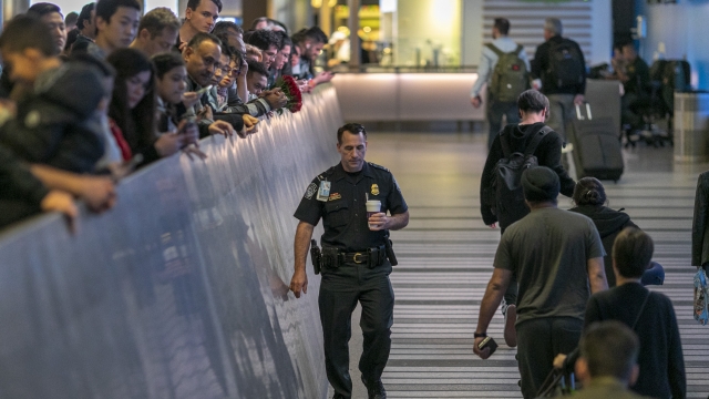An airport officer walks past international travelers arriving to Los Angeles International Airport during health screenings.