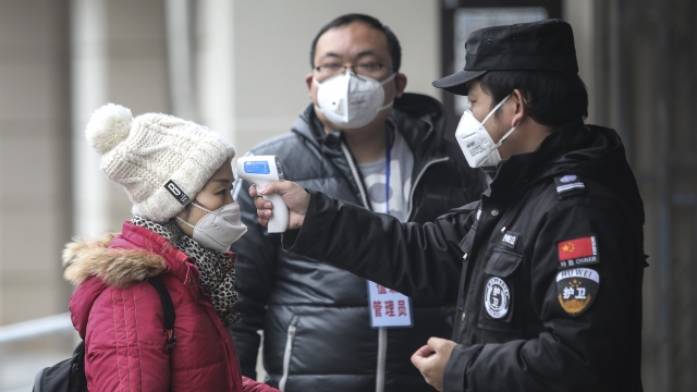 Authorities check a woman's temperature in Wuhan, China