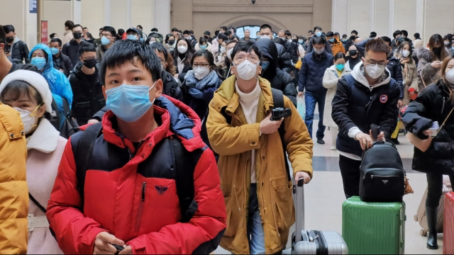 People wear face masks as they wait at a train station in Wuhan, China