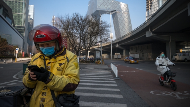 A delivery man uses his phone in the empty streets of Central Business District on February 10, 2020 in Beijing, China.