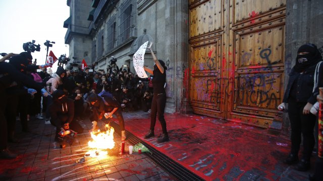 A female protester holds sign at the entrance of the National Palace in Mexico City