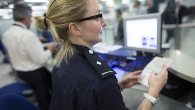 A U.K. border officer checks a passport