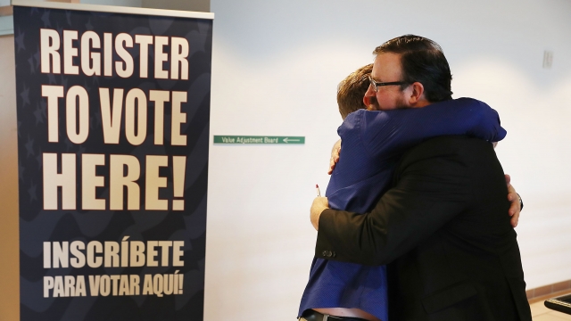 Two men with felony records hug after turning in their voter registration forms in Florida