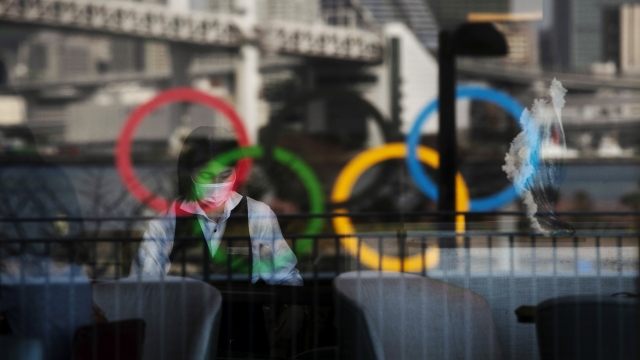 Olympic rings and people wearing protective masks