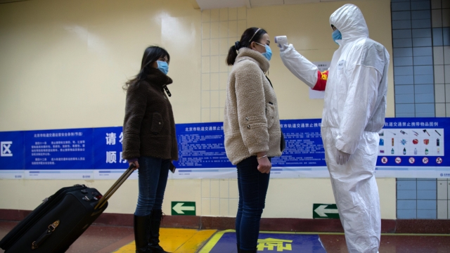 Beijing, China: A health worker checks the temperature of women