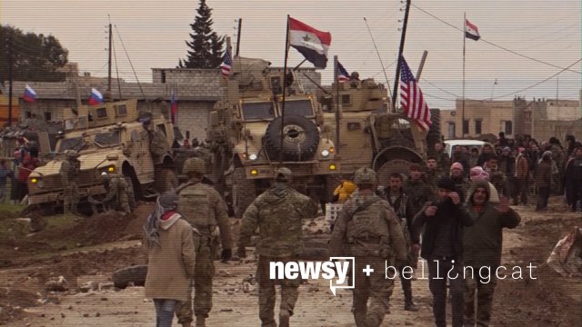 In this frame grab from video, Russian, Syrian and others gather next to a stuck American military convoy.