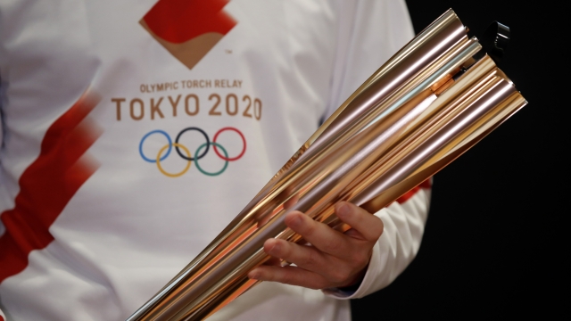 Greek singer Sakis Rouvas wears the uniform of the torch relay runners as he holds the torch of the 2020 Tokyo Olympic Games