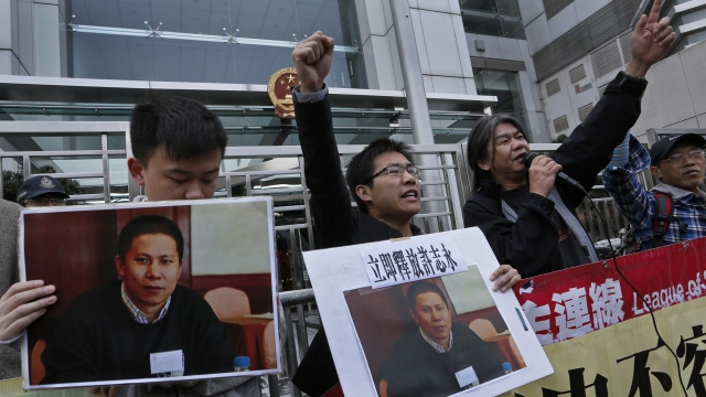 Protesters with photos of legal scholar Xu Zhiyong shout slogans against a Chinese court’s decision to sentence him in prison