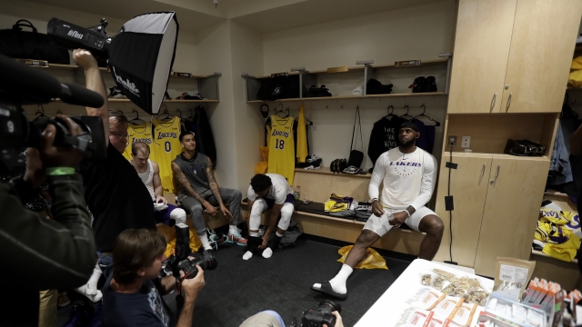 Los Angeles Lakers players sit in locker room with media