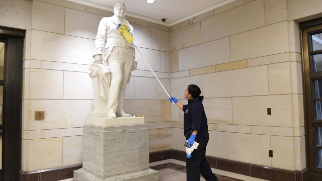 A worker dusts a statue in the Capitol Visitor Center on Capitol Hill in Washington, Thursday, March 12, 2020