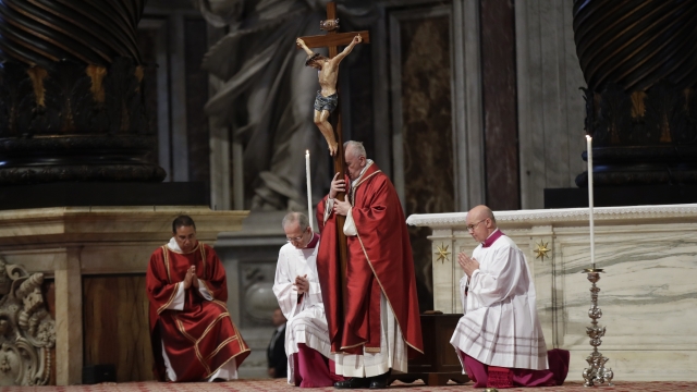 Pope Francis holds a crucifix as he celebrates Mass for the Passion of Christ.