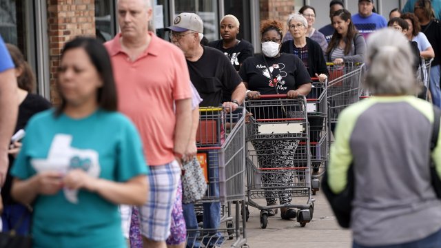 People wait for an H-E-B grocery store to open Tuesday, March 17, 2020, in Spring, Texas.