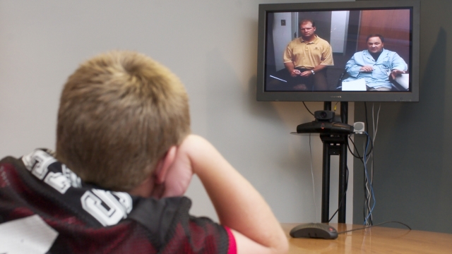 In this file image, a young boy uses telemedicine to talk to his doctor