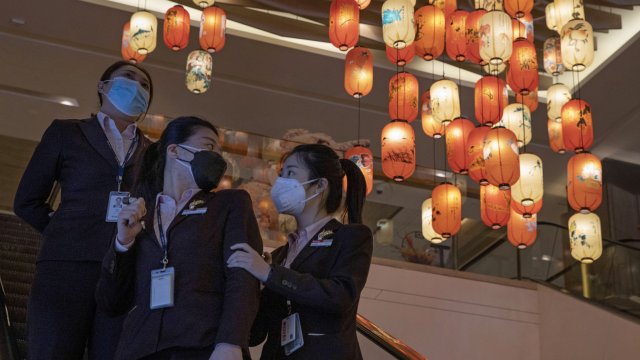 Office workers wearing masks to protect from coronavirus move past lantern decorations in an office building in Beijing.