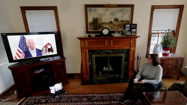 A woman watches Joe Biden on television.