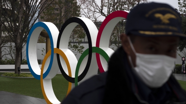A security guard walks past statue of the Olympic rings
