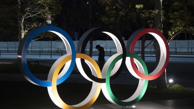 Person stands behind Olympics rings logo.
